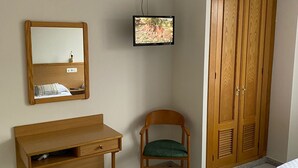 A hotel room with a bed, a wooden desk, a chair, a television, a wardrobe, and a mirror. - HOSTAL LIBERTAD (Villadangos del Paramo)