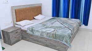 A bed with a wooden headboard, a wooden nightstand, and a patterned bedspread. - NIRMALA GARDEN (Aonla)