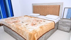A bed with a floral bedspread, a wooden headboard, and two pillows. - NIRMALA GARDEN (Aonla)