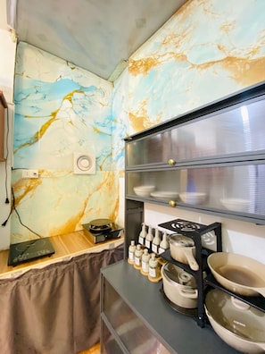 Een koelkast, een kookplaat, een vaatwasser, kookgerei, borden en bestek