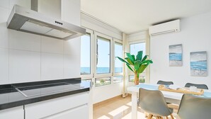 Eine moderne Küche mit Meerblick, ein Essbereich mit Tisch und Stühlen sowie eine große Pflanze.