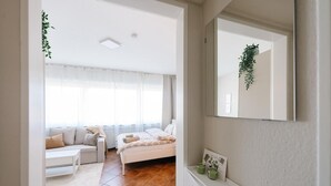 A bedroom with a bed, a bedside table, a mirror, and a window with curtains. - Apartment 'Air Fair' with Wi-Fi (Düsseldorf)