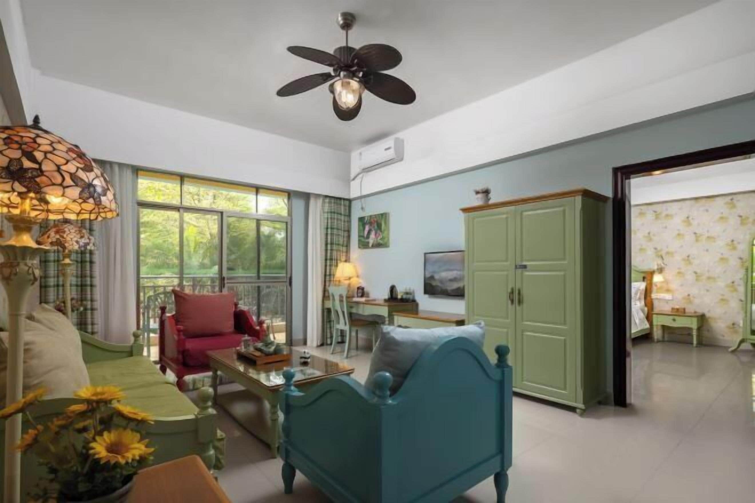 A room with a bed, a desk, a chair, a cabinet, and a ceiling fan.