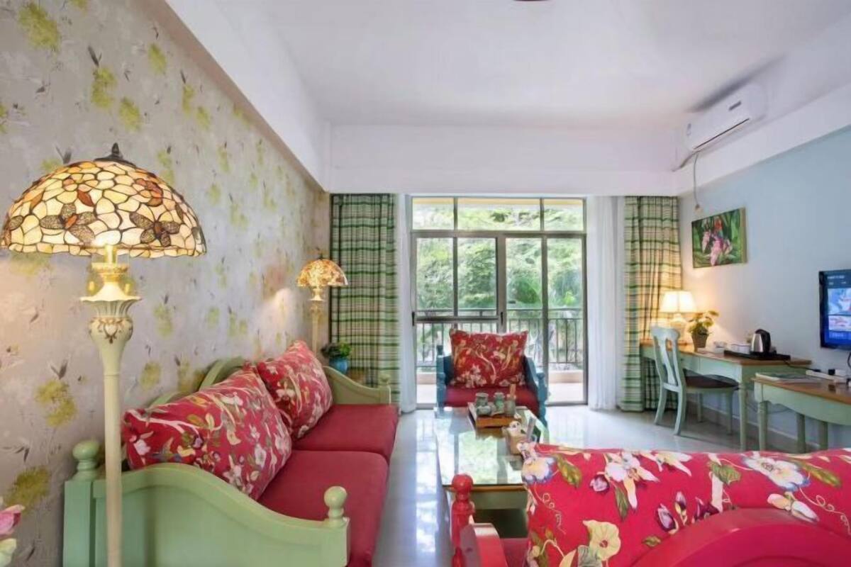 A room with a sofa, a coffee table, a desk, and a television.