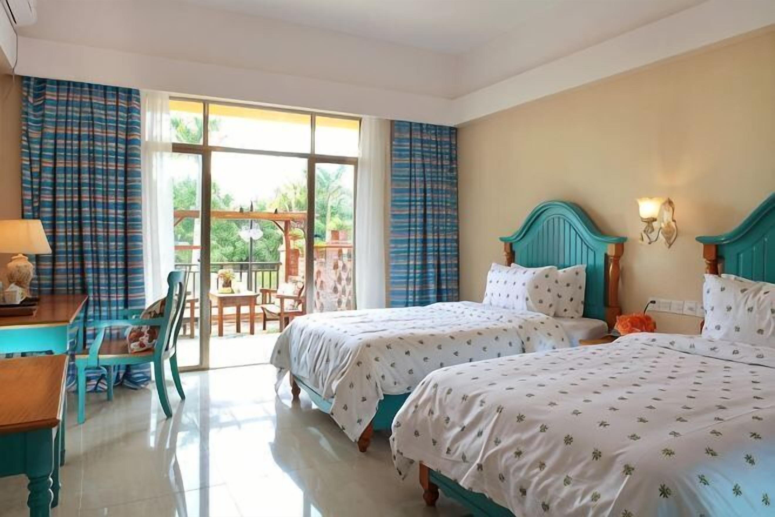 Quarto de hotel com duas camas, uma escrivaninha e vista para o exterior.