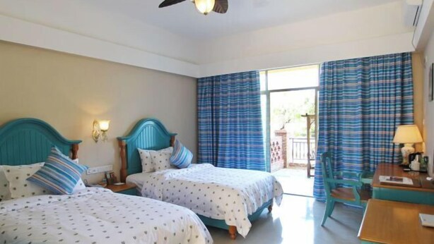 A hotel room with two beds, a ceiling fan, a table, and a chair. - Forest Inn (Hainan University, Zhangzhou Botanical Garden Thermoscience Academy) (Danzhou)