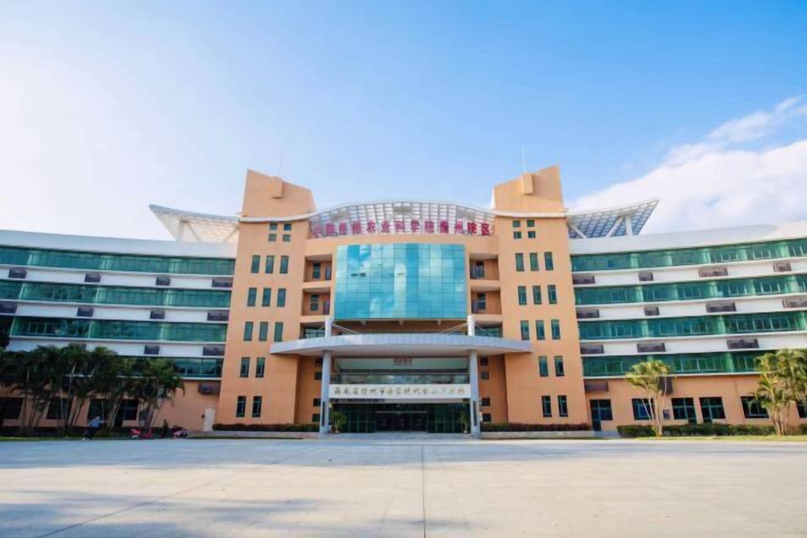 A modern building with a central glass facade and multiple floors.