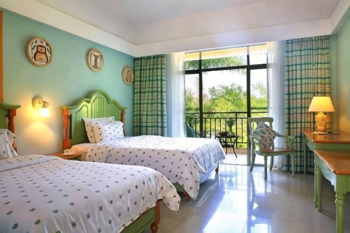 A room with two beds, a chair, a table, and a balcony with a view.