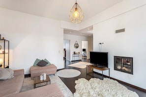 A modern living room with a sofa, a coffee table, a TV, and a fireplace.