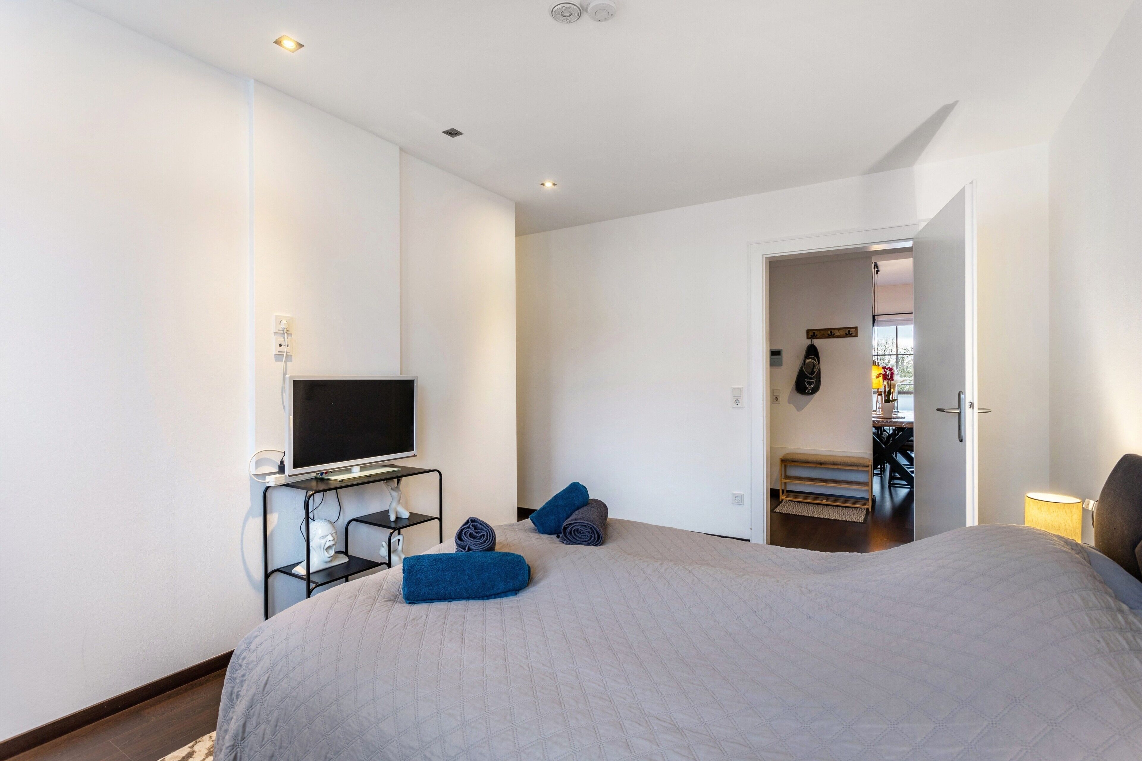 A bedroom with a bed, a TV, a desk, and a door leading to a bathroom.