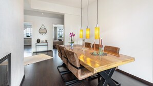 A dining area with a wooden table, leather chairs, pendant lights, and a vase with flowers. - Exclusive Loft with Fireplace, Private Sun Balcony & Wi-Fi in Bad Salzuflen (Bad Salzuflen)