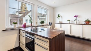A modern kitchen with a central island, large windows, and potted plants. - Exclusive Loft with Fireplace, Private Sun Balcony & Wi-Fi in Bad Salzuflen (Bad Salzuflen)