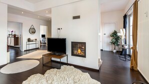 A modern living room with a fireplace, a flat-screen TV, and a large fluffy rug. - Exclusive Loft with Fireplace, Private Sun Balcony & Wi-Fi in Bad Salzuflen (Bad Salzuflen)
