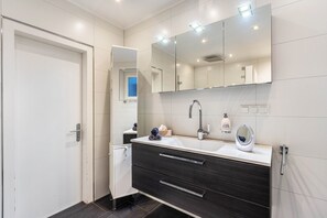 Une salle de bain moderne avec un grand miroir, un lavabo et un meuble-vasque en bois foncé.