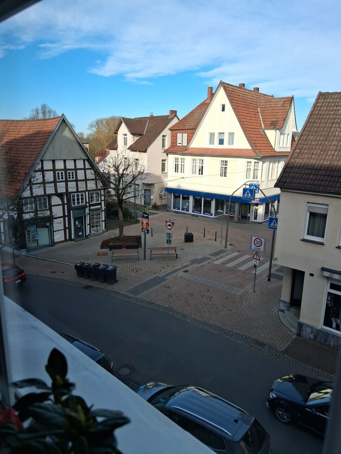 Une vue de rue avec une architecture européenne traditionnelle, un passage piéton et des voitures garées.
