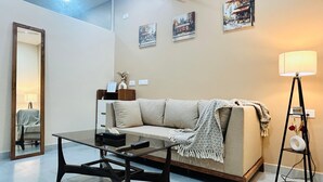 Una sala de estar con sofá, mesa de centro, lámpara y decoración en la pared.