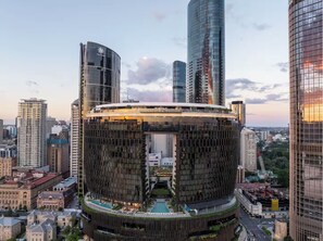A modern building with a circular design, featuring a rooftop pool and a central courtyard. - Queen's Wharf 1B+Study · City Breeze & Views (Brisbane City)