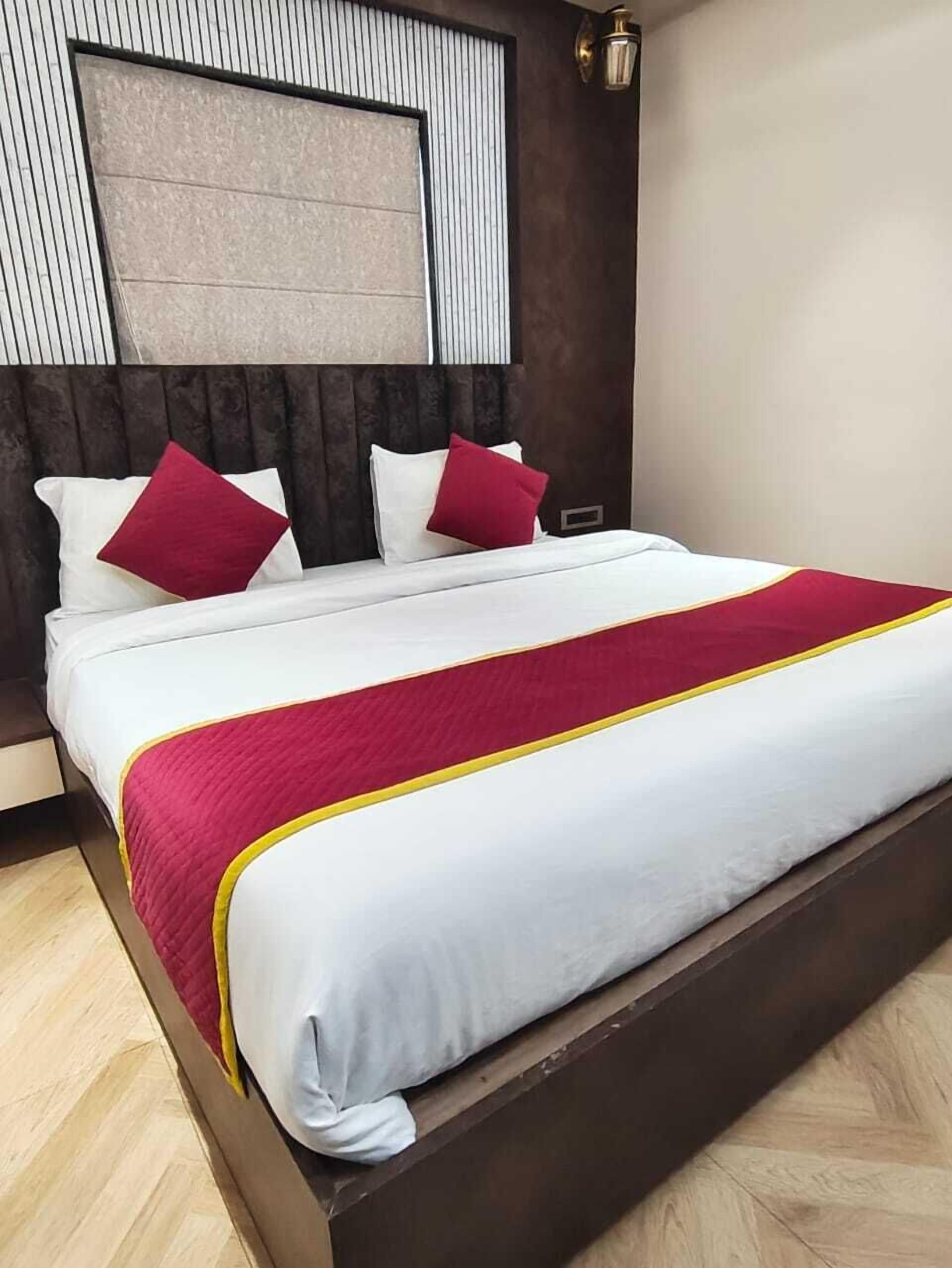 A modern hotel room with a large bed, dark wood headboard, and a view of the city skyline.