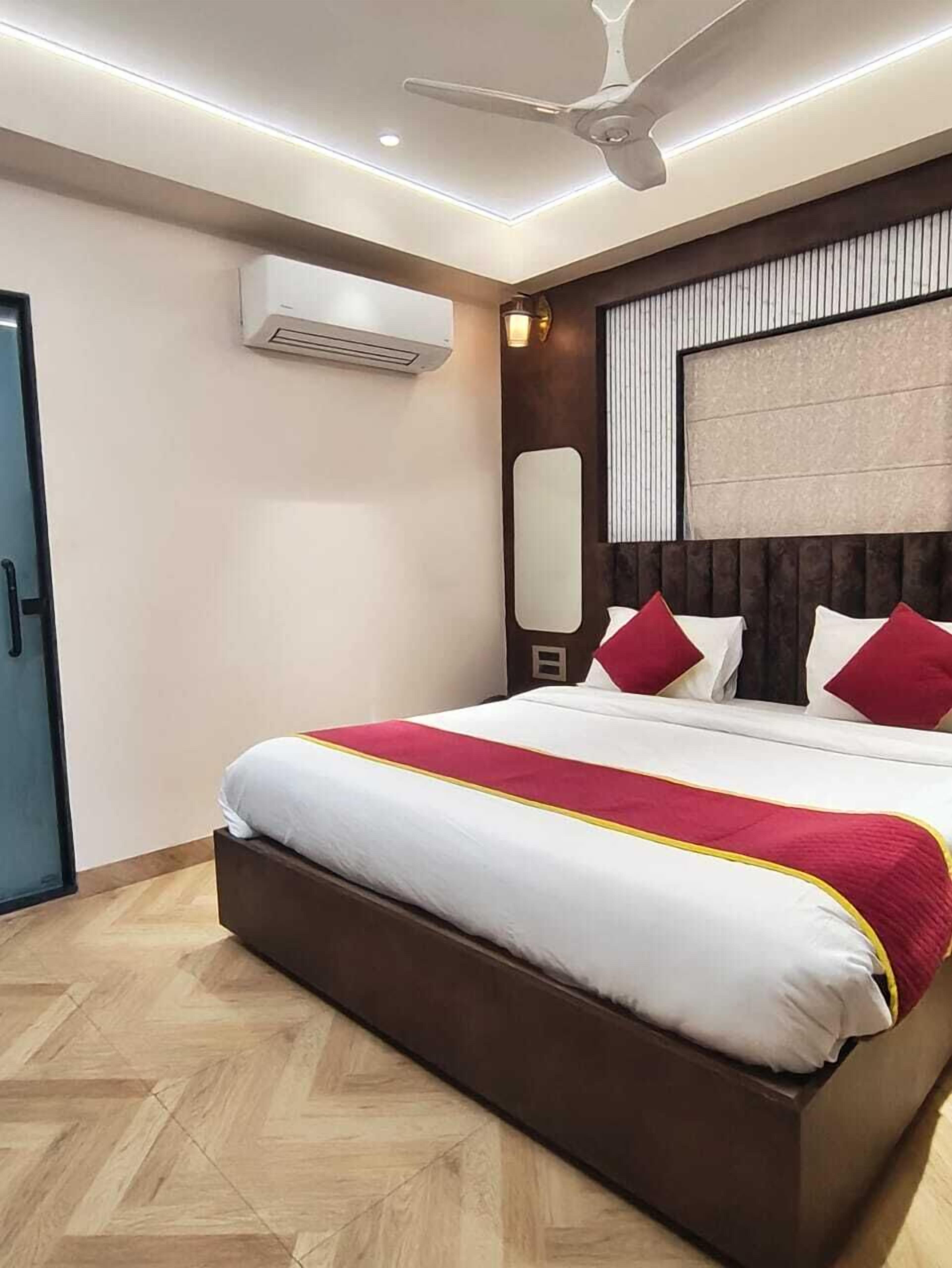 Quarto de hotel moderno com uma cama grande, um ventilador de teto e um aparelho de ar condicionado.