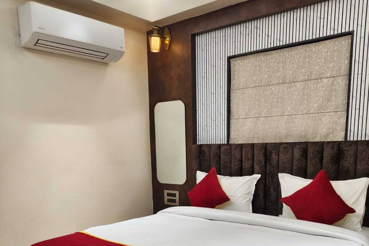 Habitació d'hotel moderna amb un llit gran, aire condicionat fixat a la paret i un mirall decoratiu.