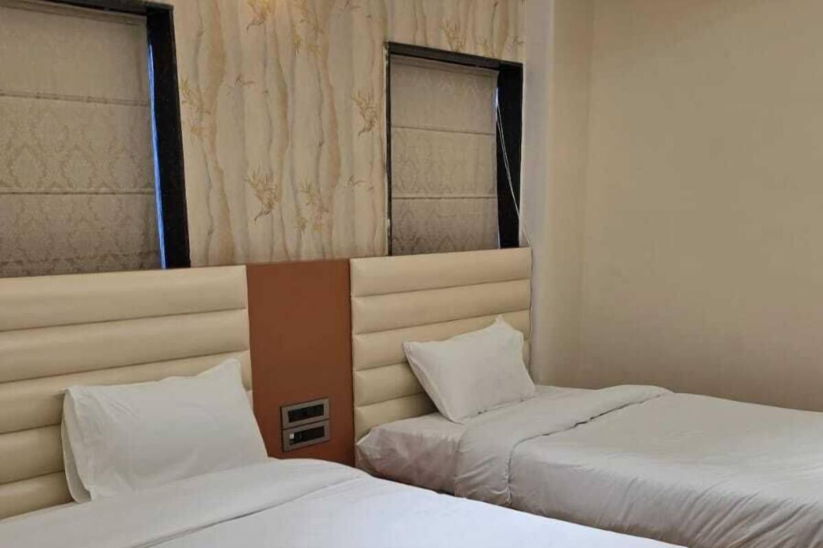 Habitació d'hotel amb dos llits, una paret amb disseny de marbre i un ventilador de sostre.