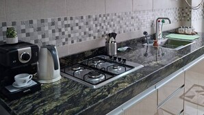 A modern kitchen with a gas stove, coffee maker, and a sink.