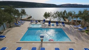 Zona de piscina amb gandules i vistes a l'aigua.