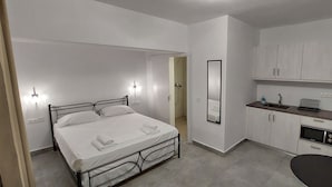 Una camera d'albergo compatta con un letto singolo, un angolo cottura e uno specchio.