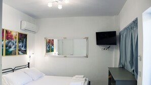 A bedroom with a bed, a dresser, a TV, and artwork on the wall. - Aenaon Corfu Luxury Apartments 03 - Aris Apt (Corfu)