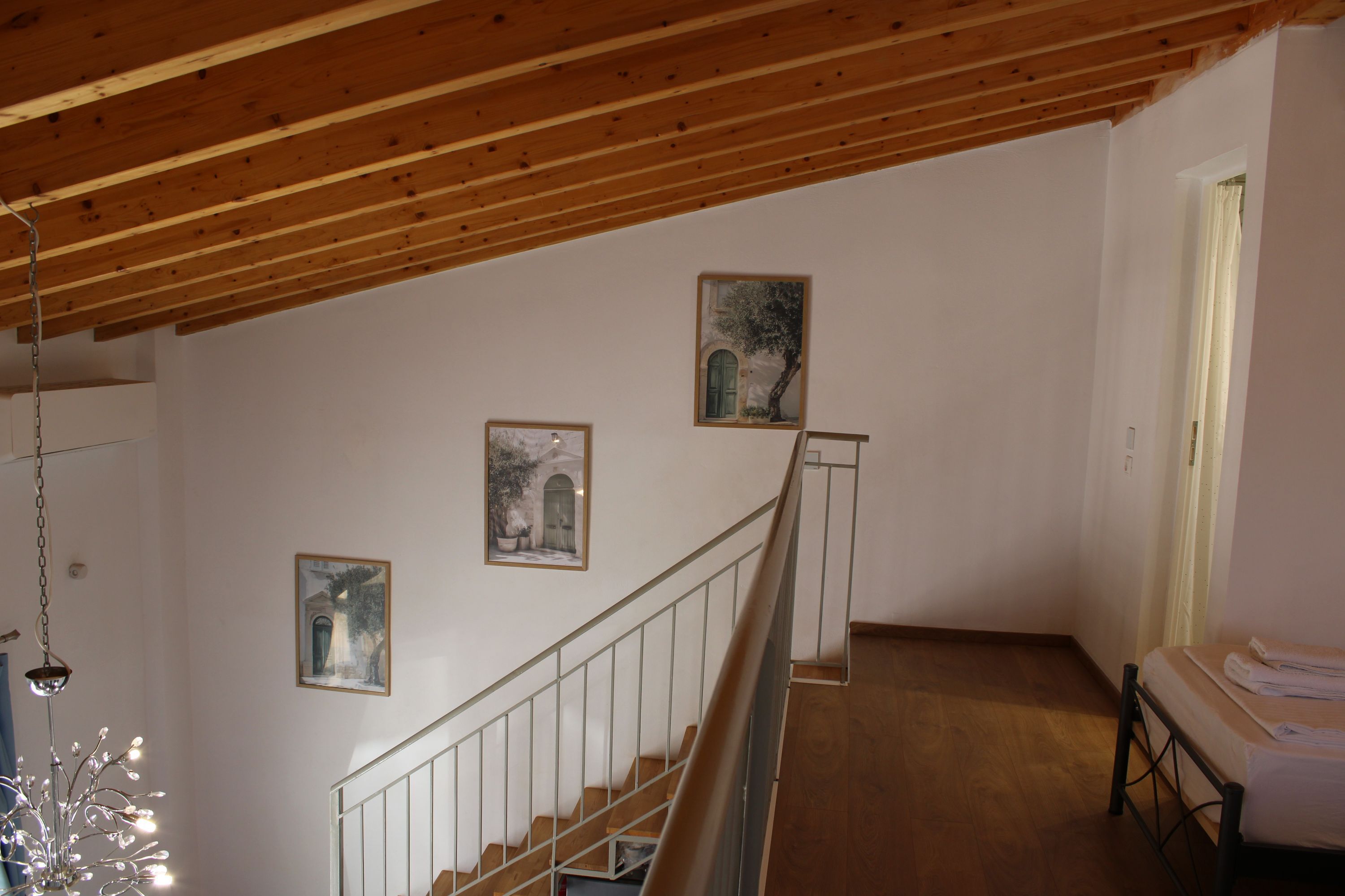 A staircase with wooden railings leading to a bedroom with a bed and a nightstand.