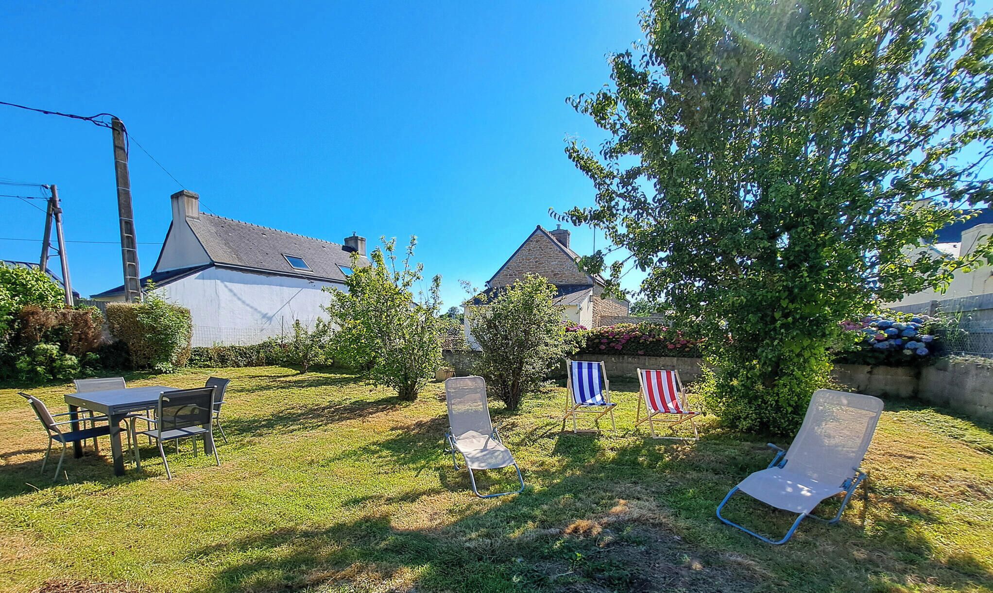 Un jardin avec une table et des chaises, un arbre et deux drapeaux.