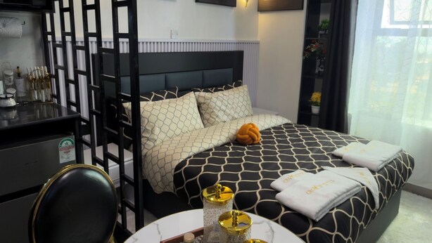 Una habitación de hotel moderna con una cama, un escritorio y una silla. Hay adornos en la pared y una araña.
