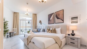 Une chambre à coucher moderne avec un grand lit, des tables de chevet, un lustre et des œuvres d’art accrochées aux murs.
