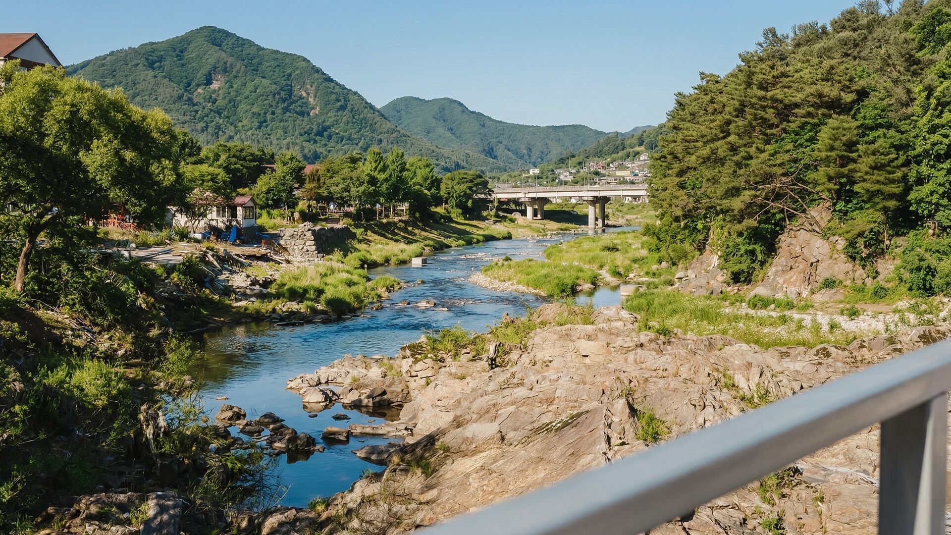 Une rivière traverse une vallée, avec un pont et des bâtiments en arrière-plan.