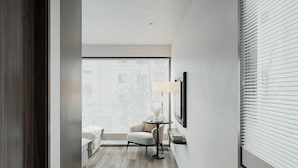 A modern hallway with a wooden floor, a seating area with a table and chairs, and large windows with blinds. - Sora Hotel Hanoi (Hanoi)