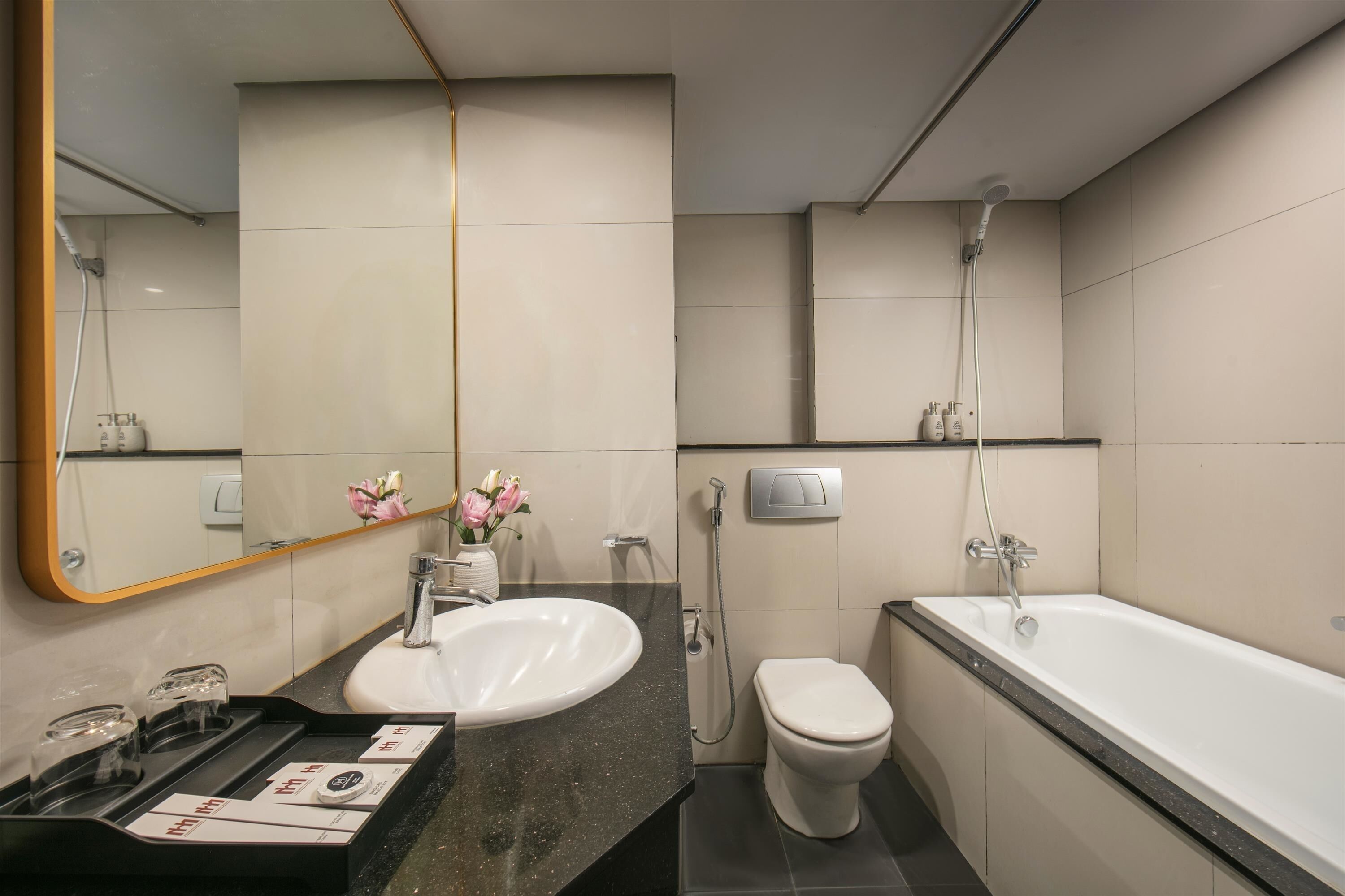 Une salle de bain moderne avec un lavabo, des toilettes et une baignoire blancs, un miroir et une douche.
