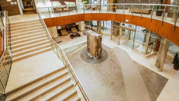 A multi-level interior with a central column, a staircase, and a seating area with sofas. - High-End 2BR/2BA Condo-Steps to Square One Mall (Mississauga)