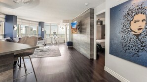 A modern living room with a dining area, large windows, and a city view. - Luxury 2BR+Den | Steps from SQ1 | Panoramic Views! (Mississauga)
