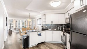 A modern kitchen with white cabinets, a black refrigerator, and a dining area with a view of the city.