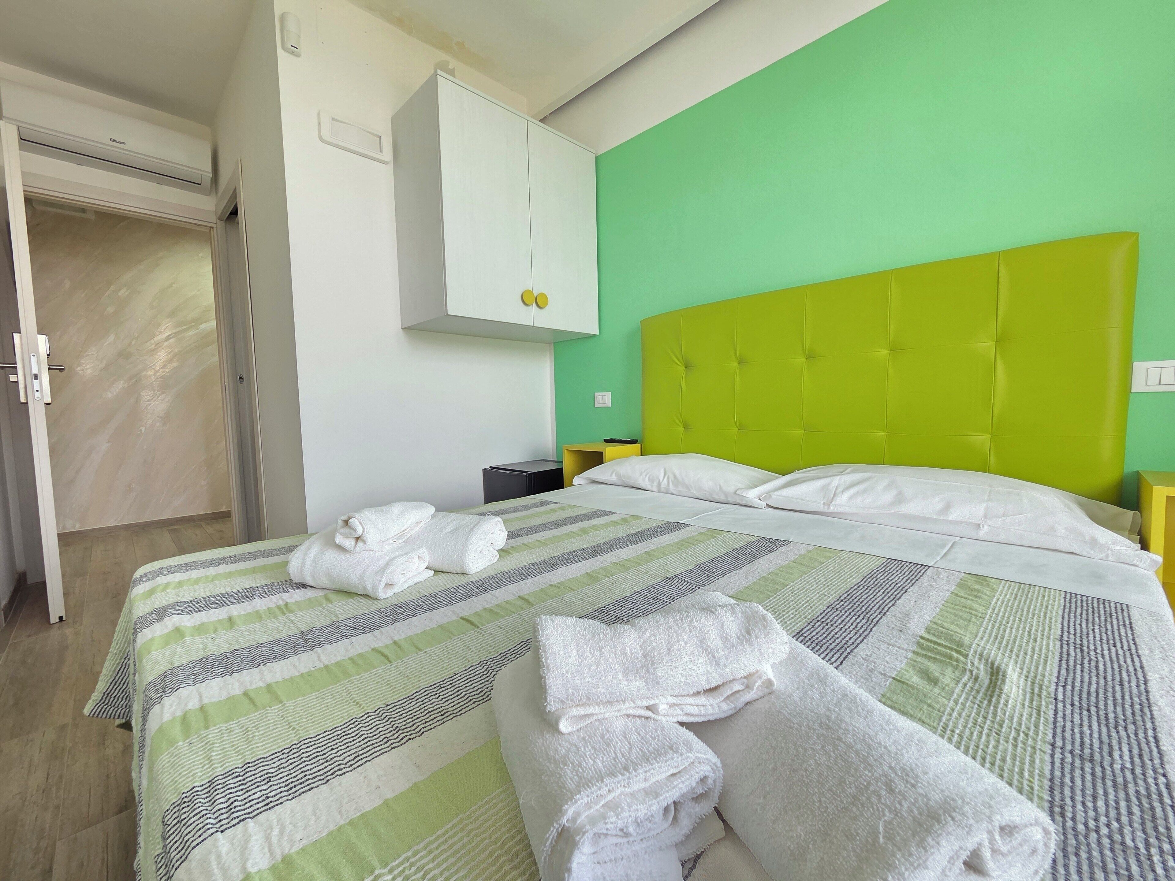Quarto de hotel com uma cama, um guarda-roupa e uma mesa de cabeceira.