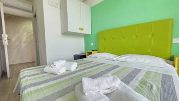 Quarto de hotel com uma cama, um guarda-roupa e uma mesa de cabeceira.