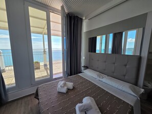 A hotel room with a large bed, a view of the sea, and a balcony with a railing. - Suite Torre Azzurra B&B Rooftop Sea View (Follonica)