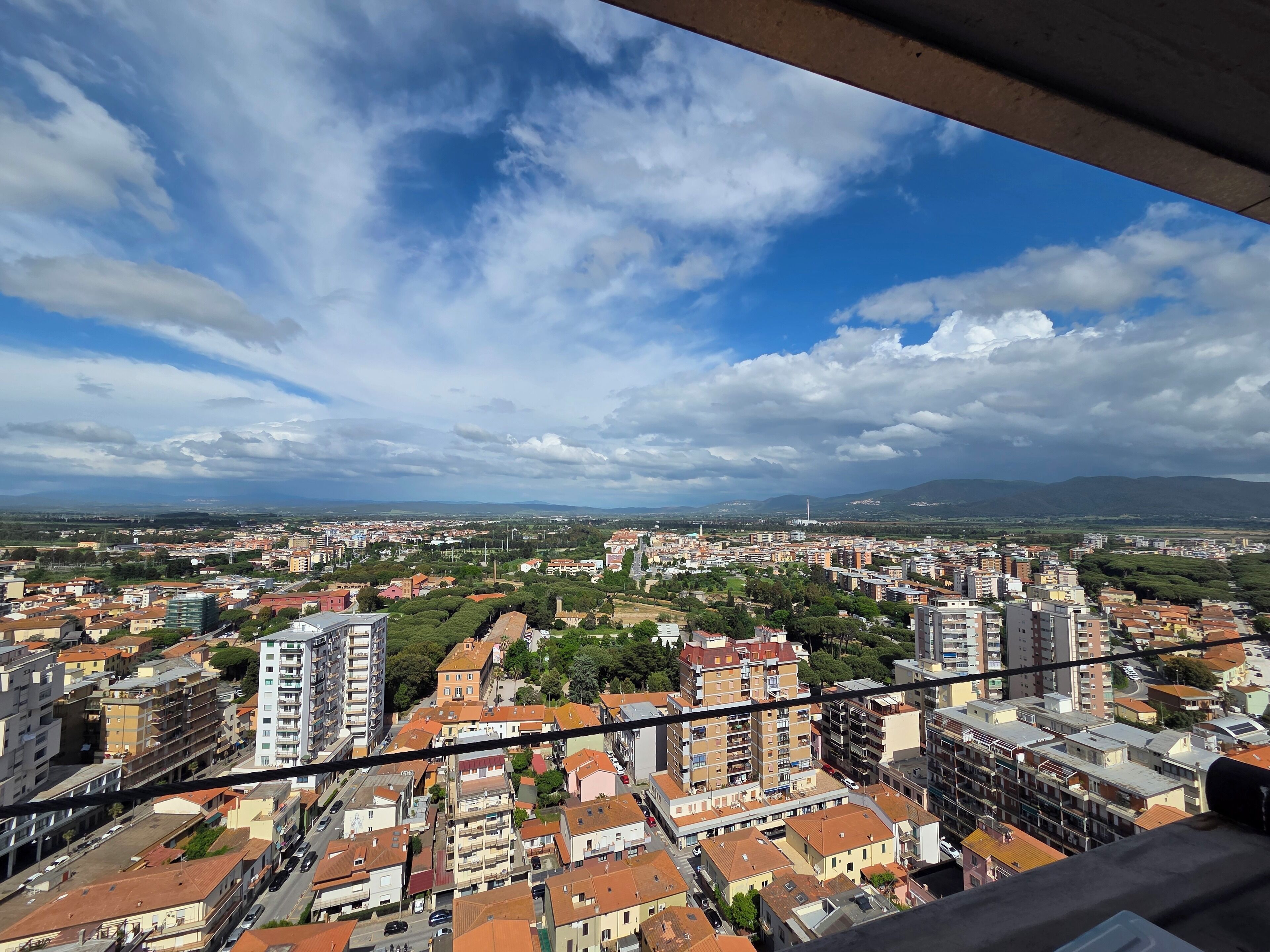 Un paysage urbain mêlant des immeubles résidentiels et commerciaux, une tour imposante et un ciel dégagé parsemé de nuages.