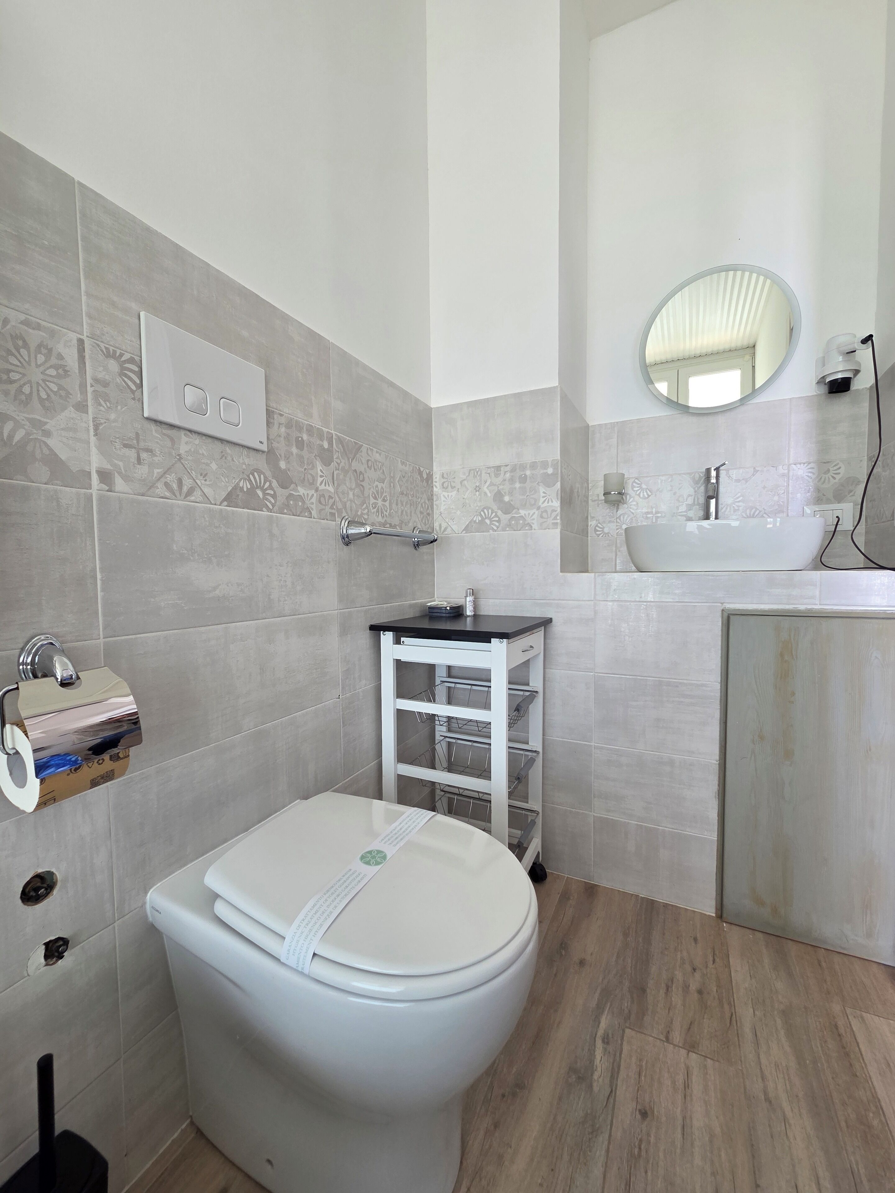 Une salle de bain équipée d’un WC, d’un lavabo, d’un miroir et d’un porte-serviettes.