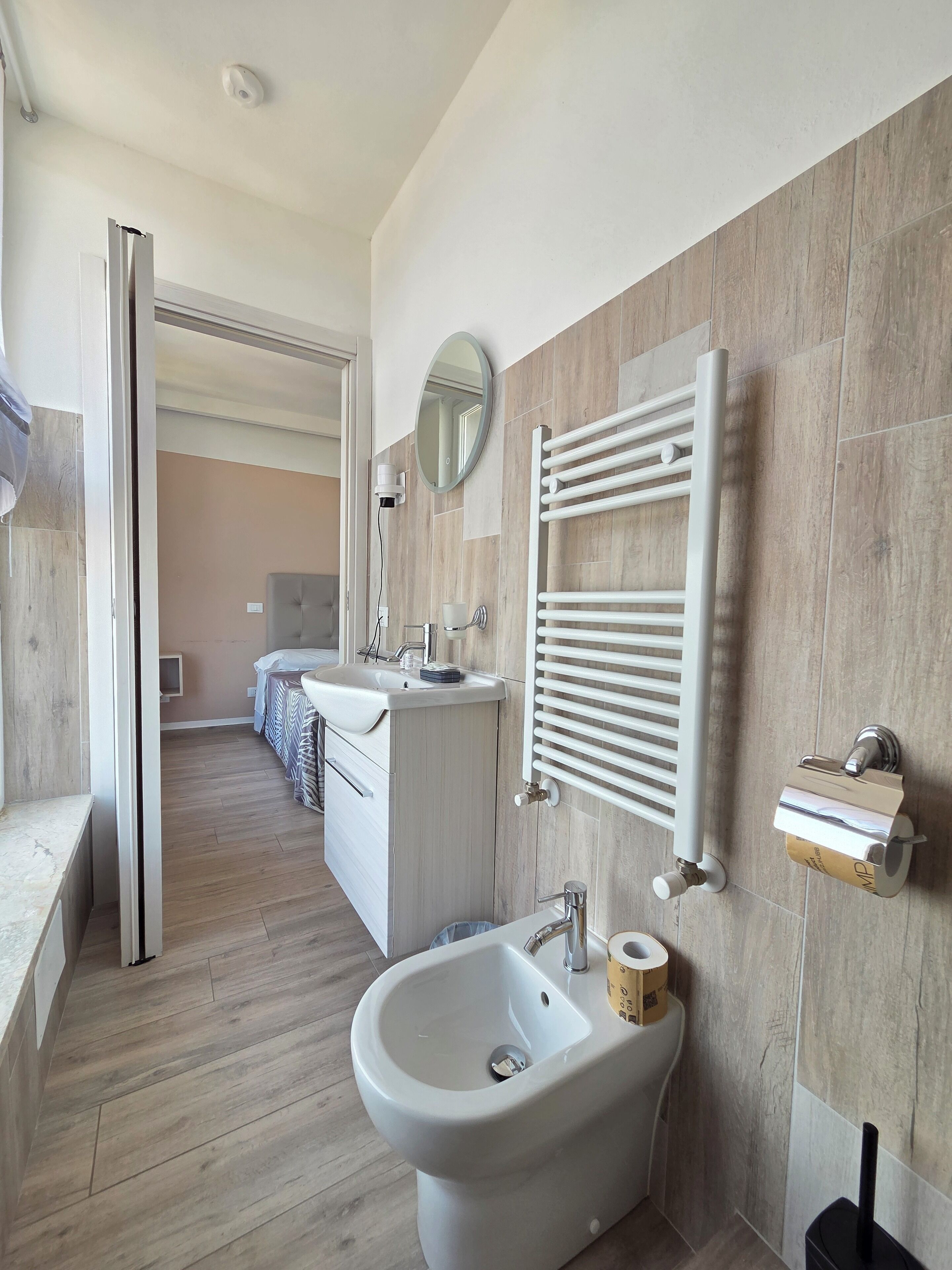 Uma casa de banho moderna com bidé, pia e porta-toalhas.