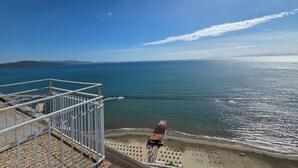 A beach view from a balcony with a railing, a sandy beach, and the ocean. - Suite Torre Azzurra B&B Rooftop Sea View (Follonica)