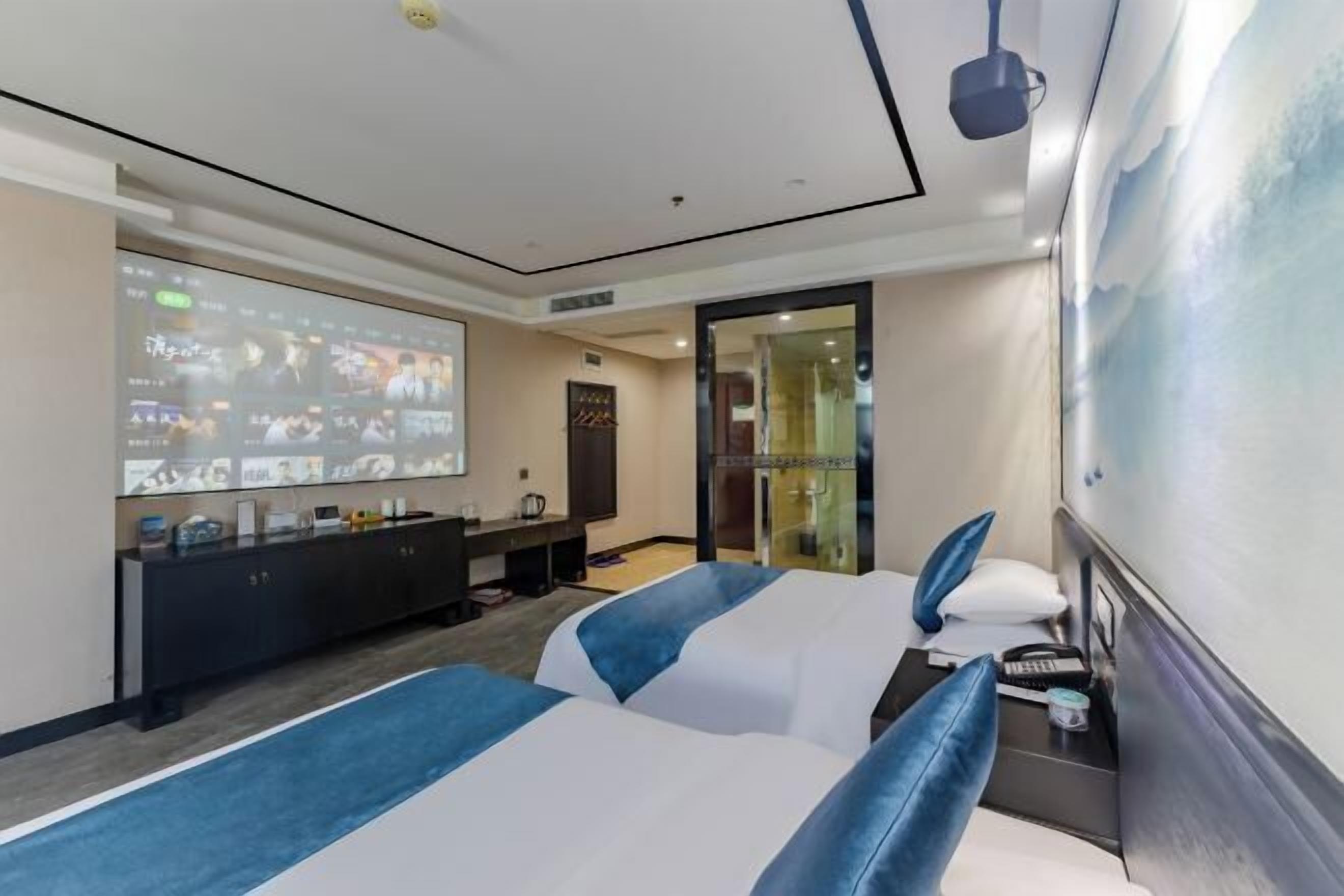 A hotel room with a bed, a desk, a TV screen, and a bathroom door.