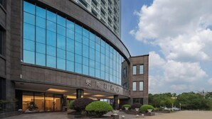 A modern building with a curved facade, large windows, and a sign with Chinese characters.