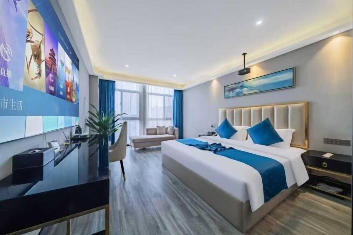Una habitación de hotel moderna con una cama grande, un escritorio, una silla y un televisor en la pared.