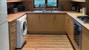 Cocina compacta con armarios de madera, lavadora integrada, un lavabo y una estufa.